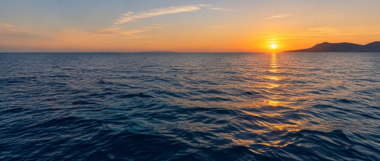 Calm Mediterranean sea at sunset, the golden sun low on the horizon off the Maltese coast