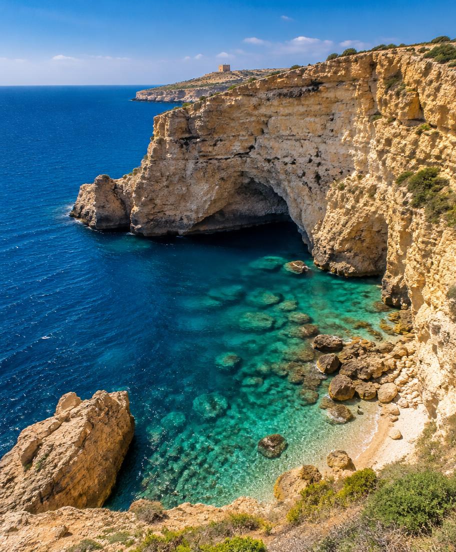Golden limestone cliffs and a turquoise cove on the coast of Malta
